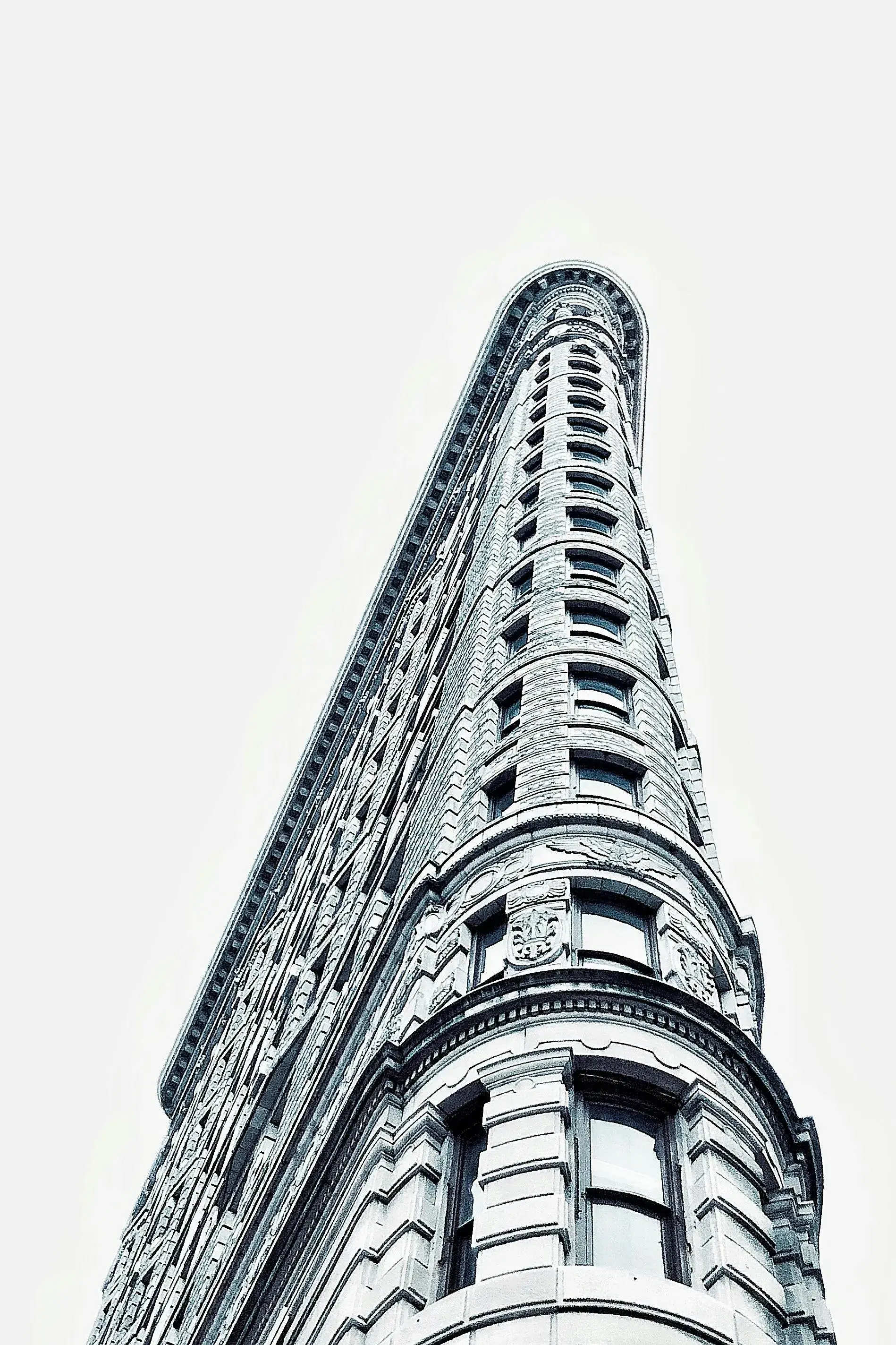 Imagem de um edifício alto e estreito, com arquitetura clássica e detalhes ornamentais, visto de baixo para cima.